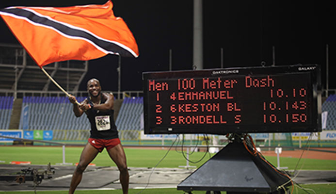 NEW SPRINT KING Emmanuel Callender of Memphis Pioneers waves the national flag in celebration of his triumph in the men's 100 metres sprint finals during the NAAA NGC/Sagicor National Championships at the Hasely Crawford Stadium on Saturday night. Callender clocked 10.10 seconds. Photo: Allan V. Crane/CA-images
