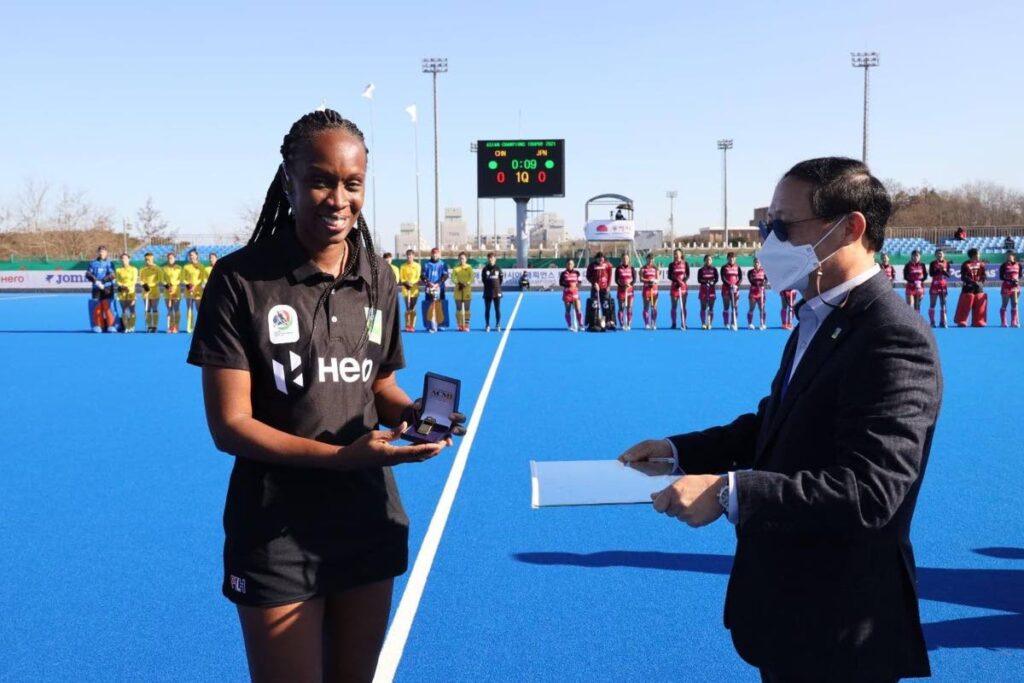 Veteran TT hockey umpire Ayanna McClean, left, is presented with the International Hockey Federation’s golden whistle after she officiated her 100th game as an international umpire on Sunday. - Courtesy: Asian Hockey Federation