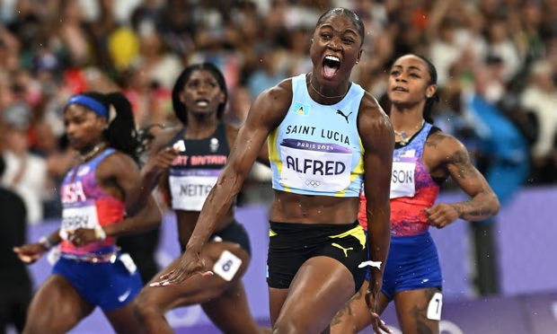 Julien Alfred celebrates after crossing the 100m finish line ahead of Sha’Carri Richardson (right) and Melissa Jefferson (left). Photograph: Dylan Martinez/Reuters (Image obtained at theguardian.com)