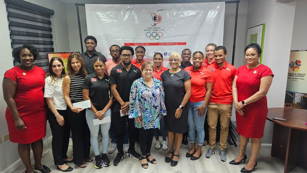 rinidad and Tobago athletes and representatives share a photo after collecting their monetary rewards for medalling at the Central American and Caribbean (CAC) Games in Santo Domingo, Dominican Republic last July/August at a presentation ceremony held at the Trinidad and Tobago Olympic Committee Olympic House, Woodford Street, Port-of-Spain on Tuesday. In photo from back-row left are Danell James (track cycling), Akil Campbell (track cycling), Nicolette Osborne (netball), Shantel Seemungal (netball), Jabari Perez (hockey), and Kira Rothwell (netball). Standing in front-row from left are Kwanieze John-Felix, T&T Olympic Committee Athletes Commission Chairman, Jessica Costa-Ouditt (on behalf of Alexi Costa-Ramirez), Tracy Carter (on behalf of Dylan Carter), Kyra Williams (track cycling), Ryan D’Abreau (track cycling), Jennifer Arrindell (on behalf of Kelly-Ann Arrindell), Diane Henderson, President of the T&T Olympic Committee (T&TOC), Rayann Bristol (netball), and Caleb Guiseppi (hockey).  PHOTO: NIGEL SIMON (Image obtained at guardian.co.tt)